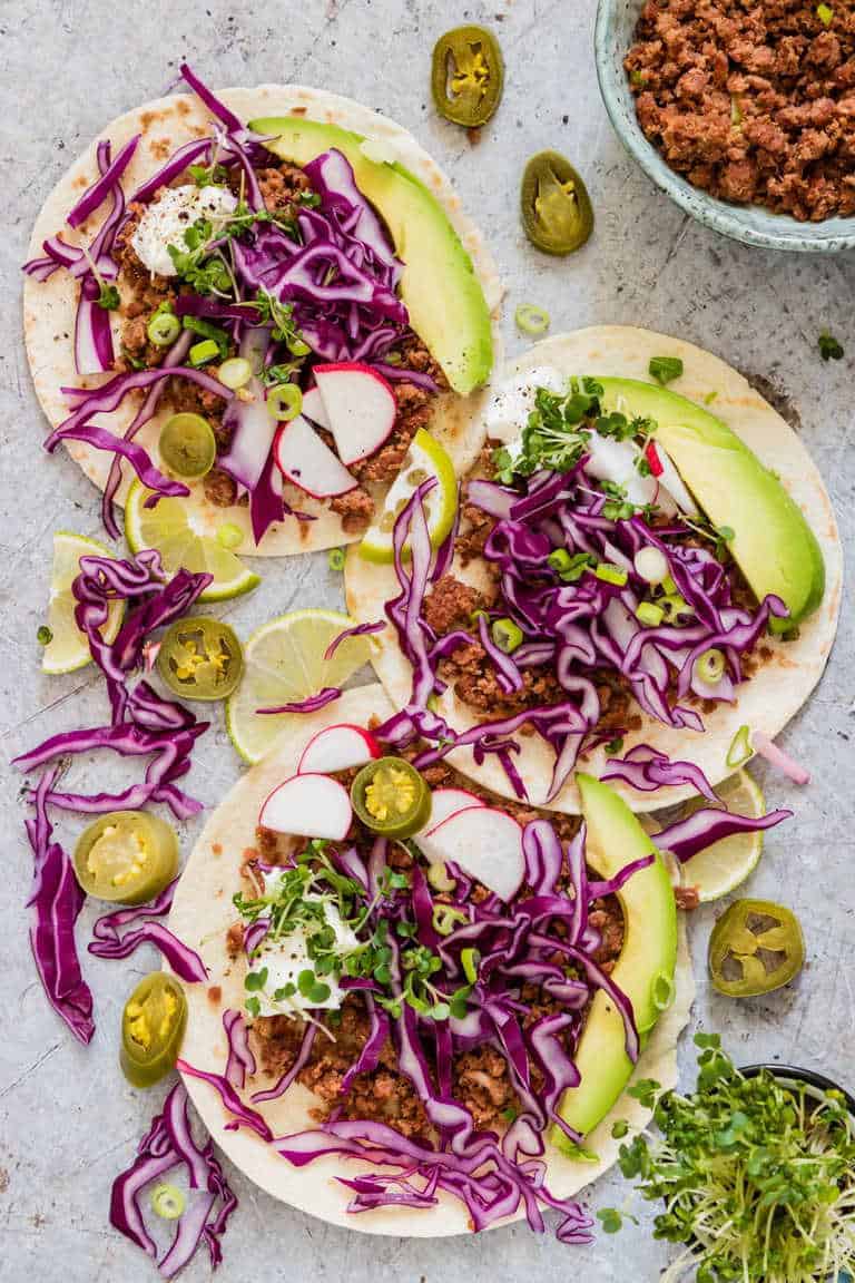 overhead shot of corned beef tacos with assortments of vegetables and corned beef over corn tortillas with cabbage, avocado, jalopenos and spring onions