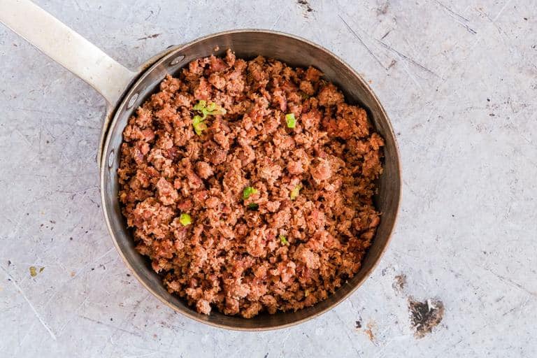 overhead view of canned corned beef cooked in pan with spring onions