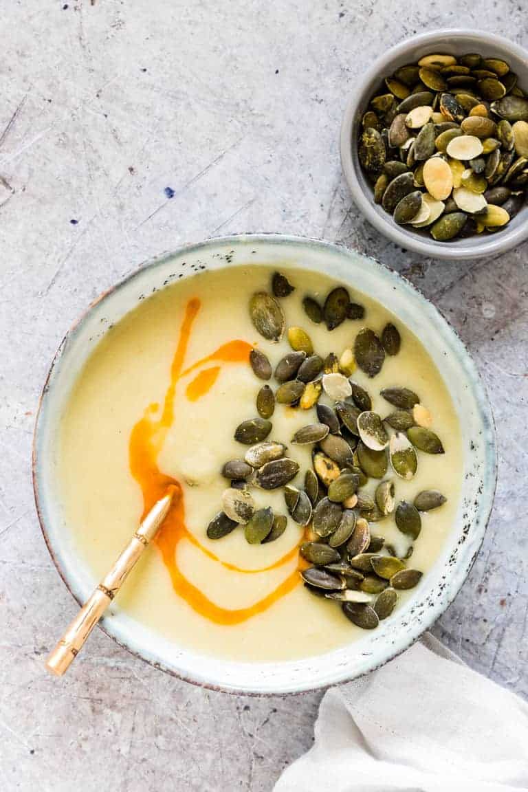 Instant Pot Potato Soup in four bowls, with pumpkin seeds and chilli oil with a spoon
