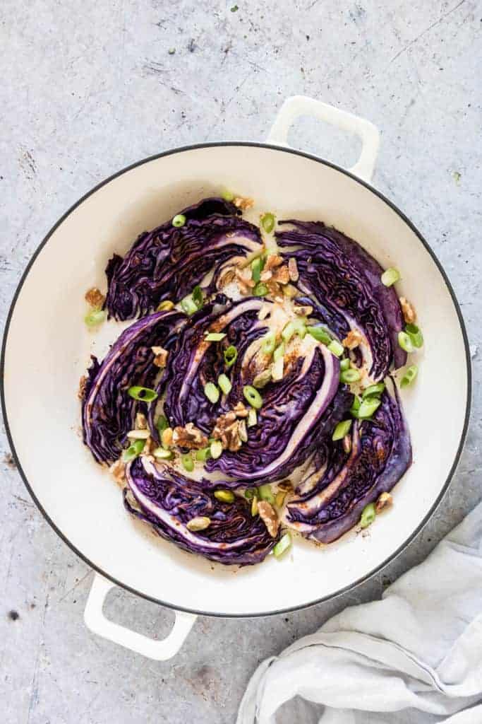 Roasted red cabbage in a pot with walnuts, spring onions, cloth