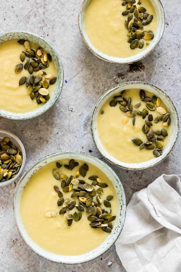 Instant Pot Potato Soup in four bowls, topped with pumpkin seeds and a grey cloth napkin