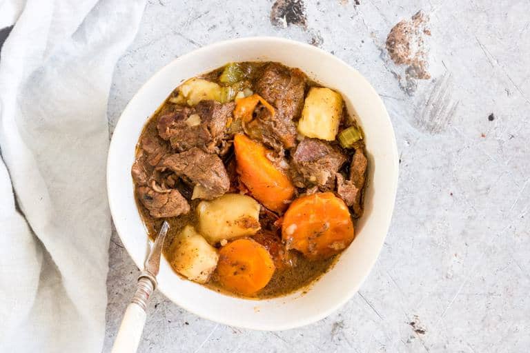 Pressure Cooker Beef Stew recipe in a bowl with a spoon and cloth next to it