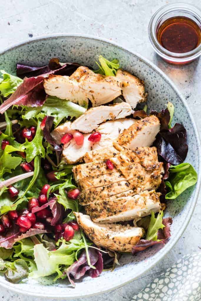 Overhead shot of a salad with slice chicken breast, salad greens and pomegranate