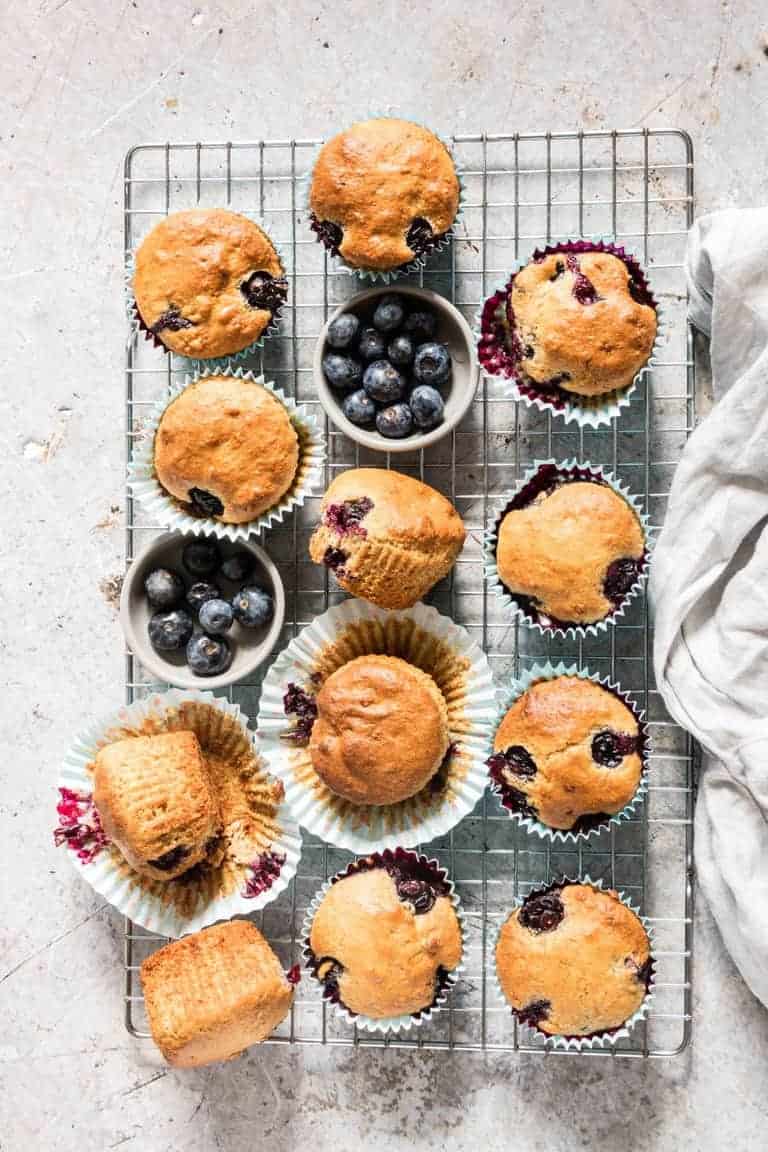 overhead shot of Vegan Blueberry Muffins with blueberries on a cooling rack with a cloth