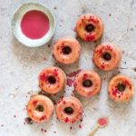 Glazed donuts with a raspberry glaze and a teaspoon