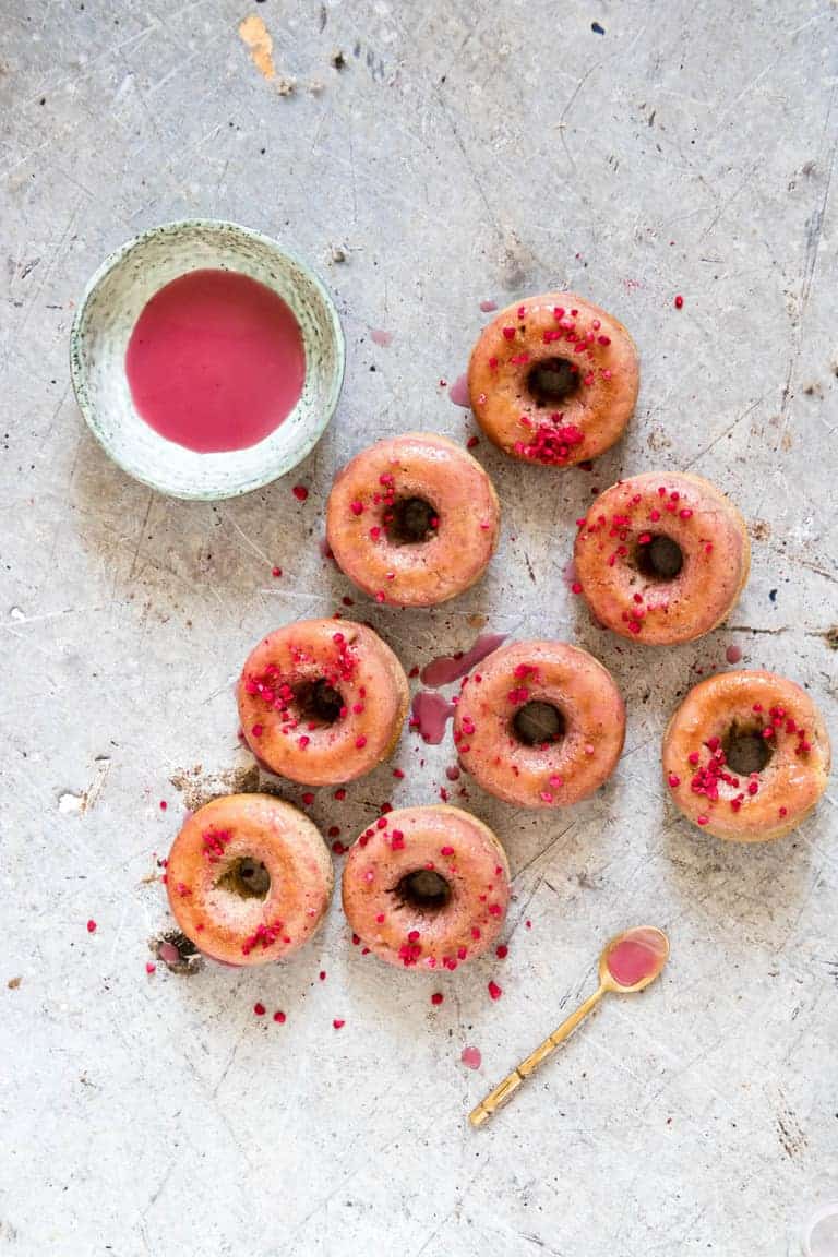 Glazed donuts with a raspberry glaze and a teaspoon