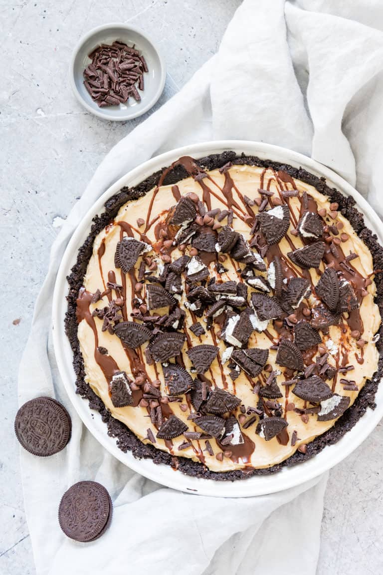 A peanut butter pie on a table topped with oreos and chocolate