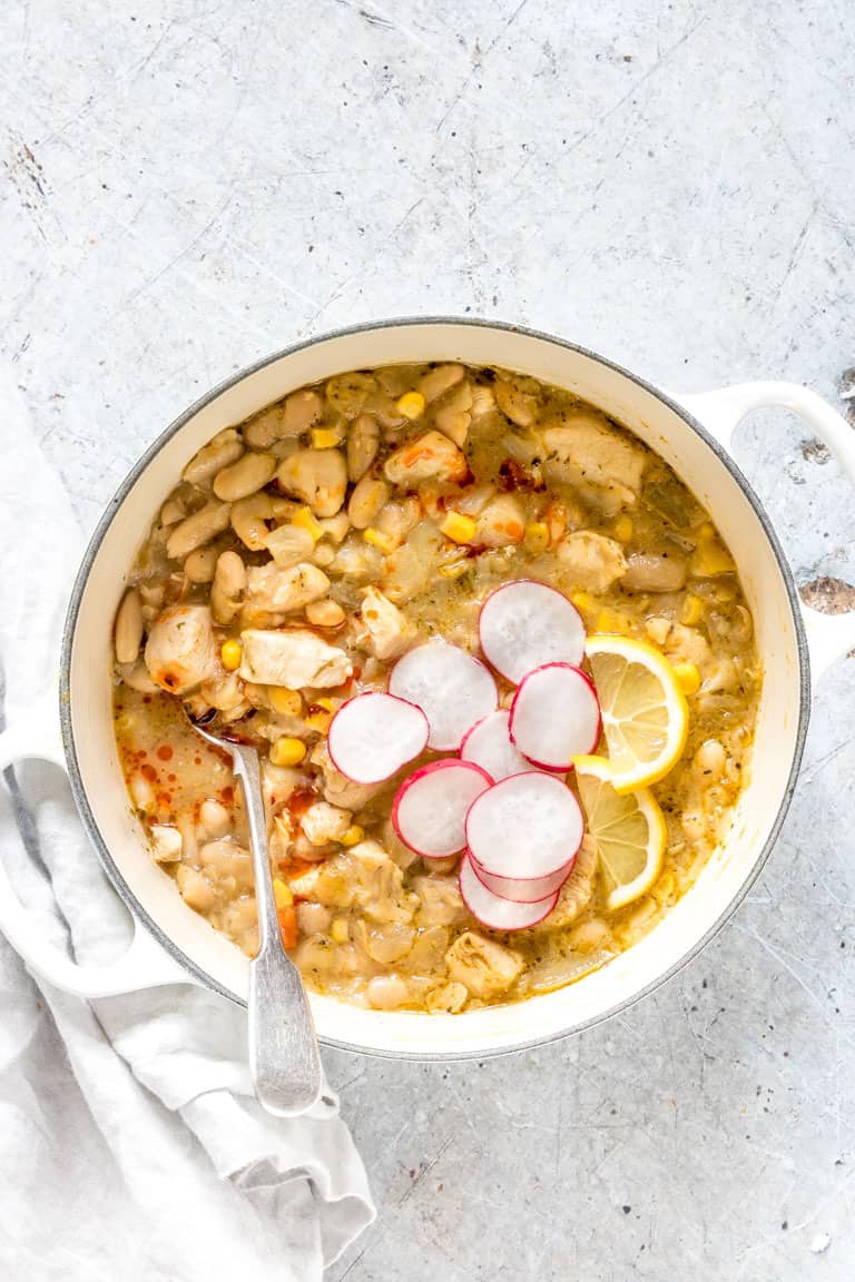pot of white chicken chili recipe garnished with radishes next to a white towel