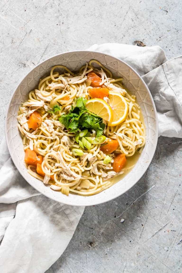 overhead view of instant pot chicken soup in a white bowl on top of a towel