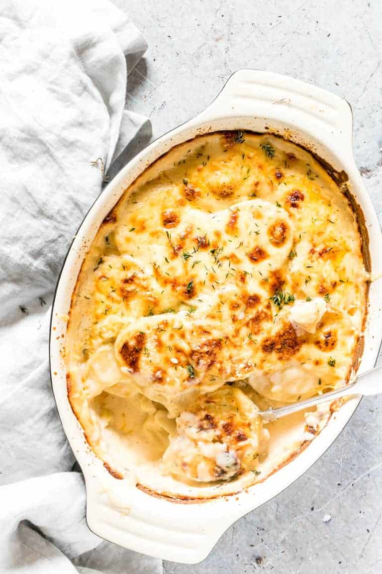 top down view of scalloped potatoes in baking dish with serving spoon inside