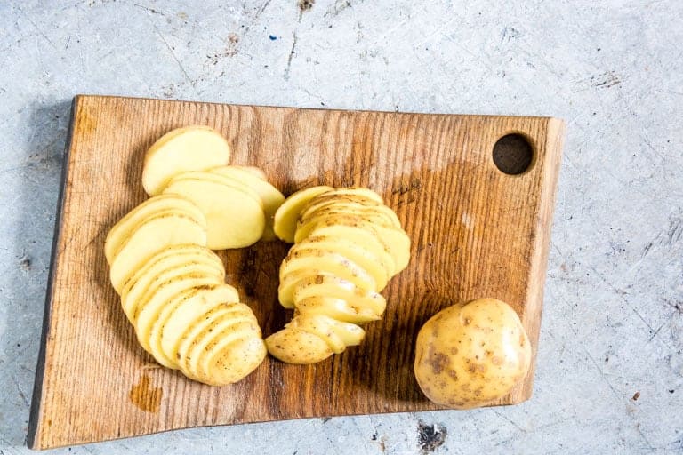 sliced potatoes on a cutting board for scalloped potatoes
