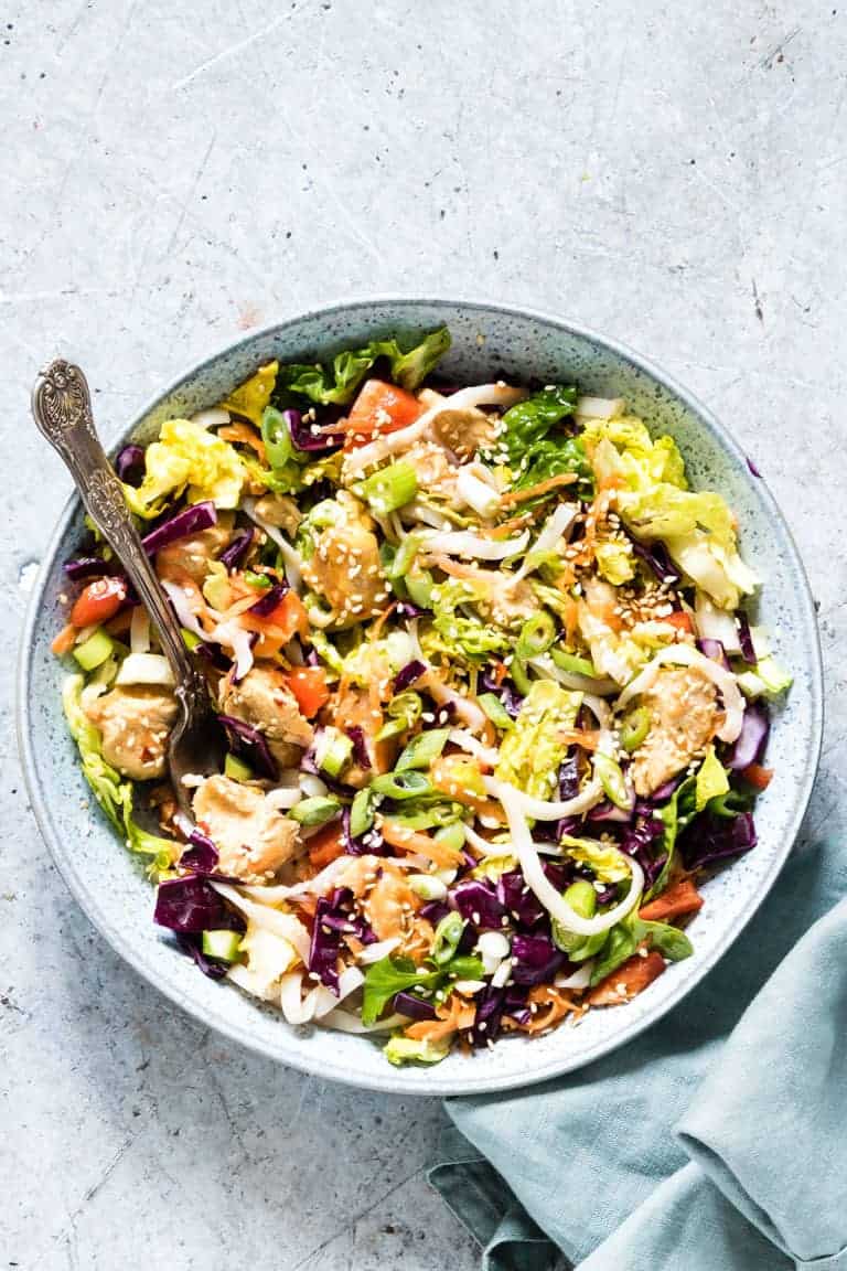 overhead view of chinese chicken salad next to kitchen towel with fork sticking out