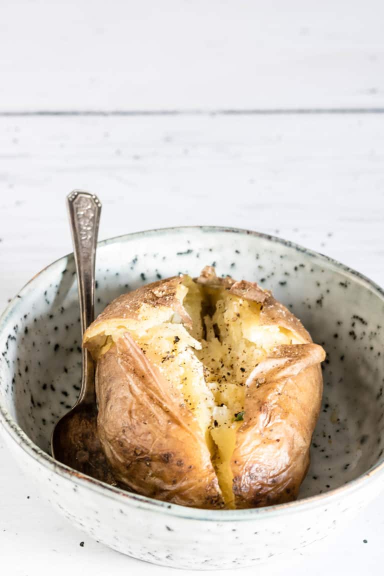 a baked potatosplit, with ground pepper in a bowl