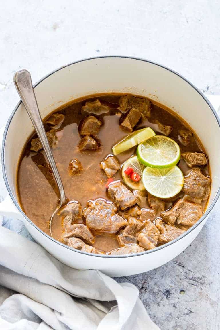 nigerian pepper soup in a pot with a spoon and lime