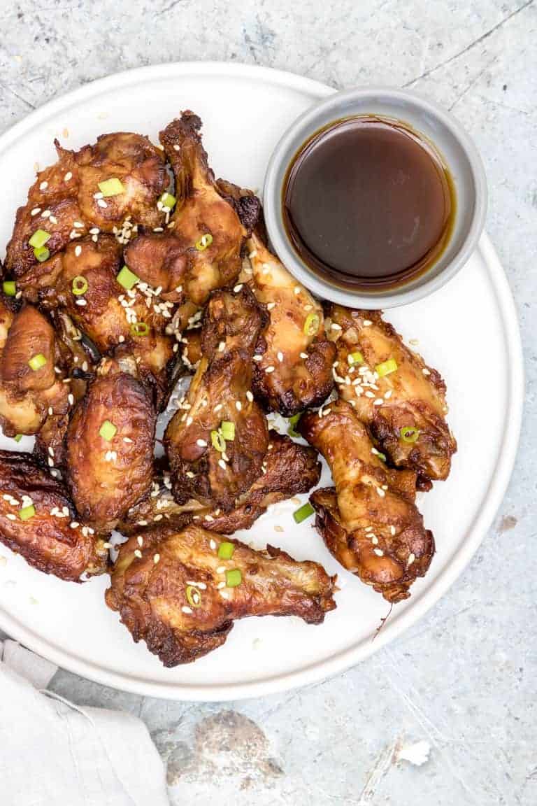 overhead view of instant pot chicken wings on a white plate with soy sauce