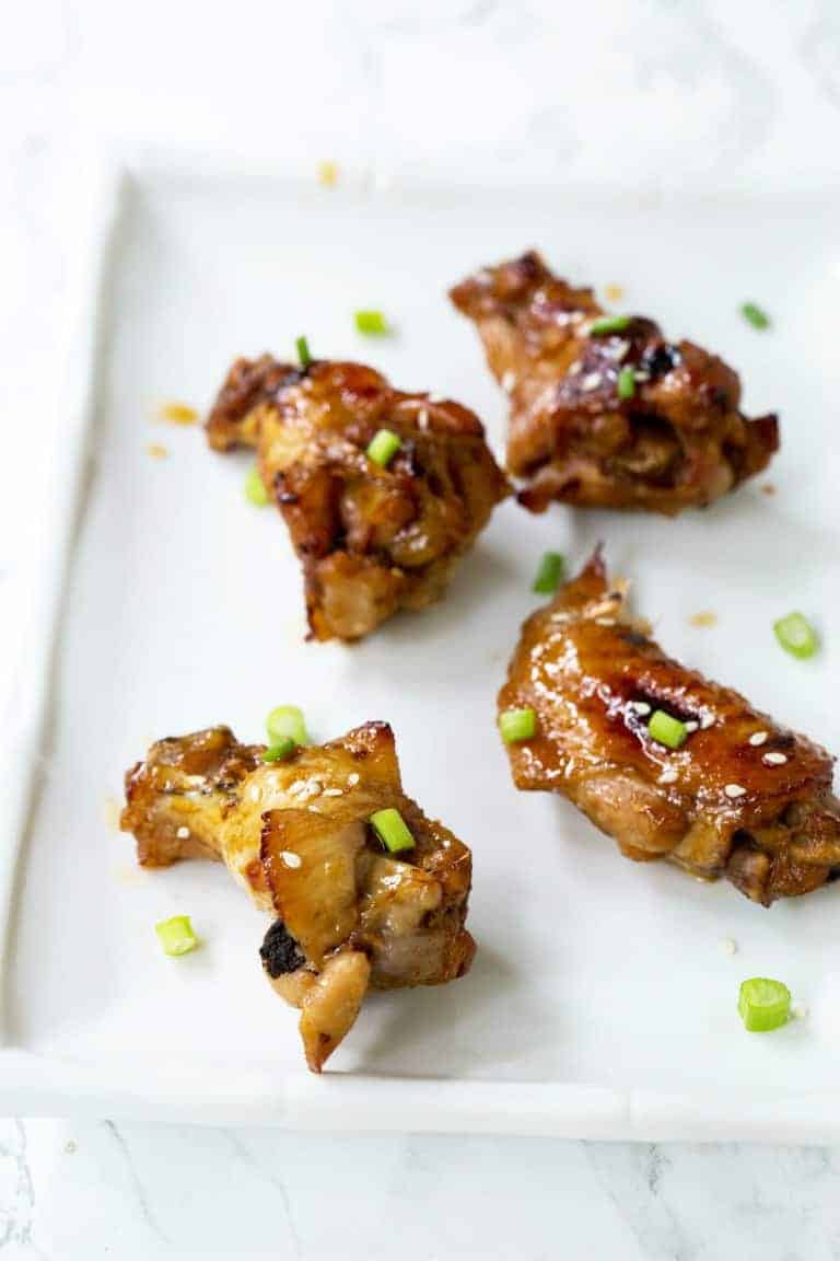 four instant pot chicken wings on a white plate with honey chilli sauce