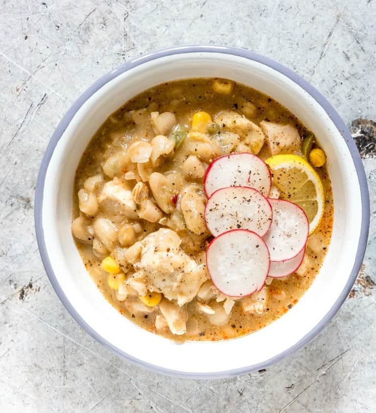 bowl of instant pot white chicken chili on a table with garnishes