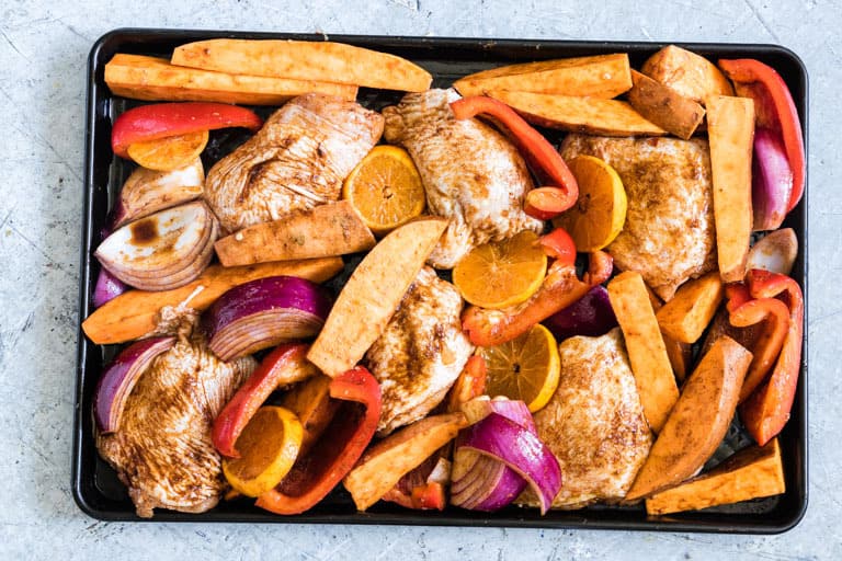 Uncooked Sheet pan Baked Chicken Thighs and Sweet Potato on a table