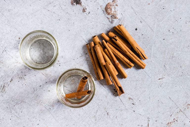 Cinnamon sticks and two jars filled with vodka ready for making Instant Pot Cinnamon Extract placed on a countertop