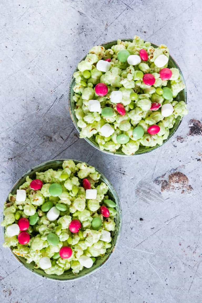 top down view of two ceramic bowls filled with Grinch Popcorn on a countertop and ready to serve