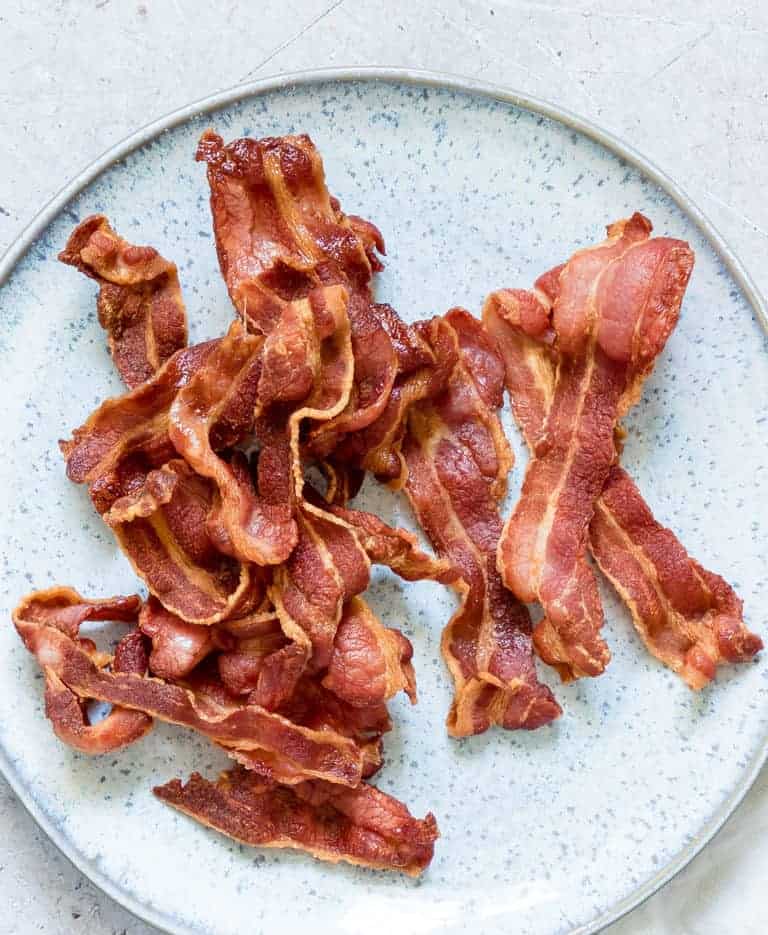 close up view of cooked Crispy Air Fryer Bacon (air fry bacon) served on a light blue ceramic plate