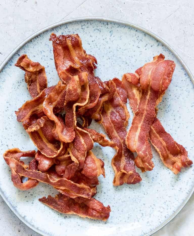 close up view of cooked Crispy Air Fryer Bacon served on a light blue ceramic plate