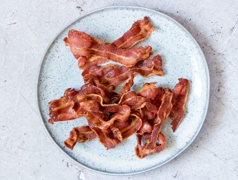 strips of cooked crispy air fry bacon served on a light blue ceramic plate