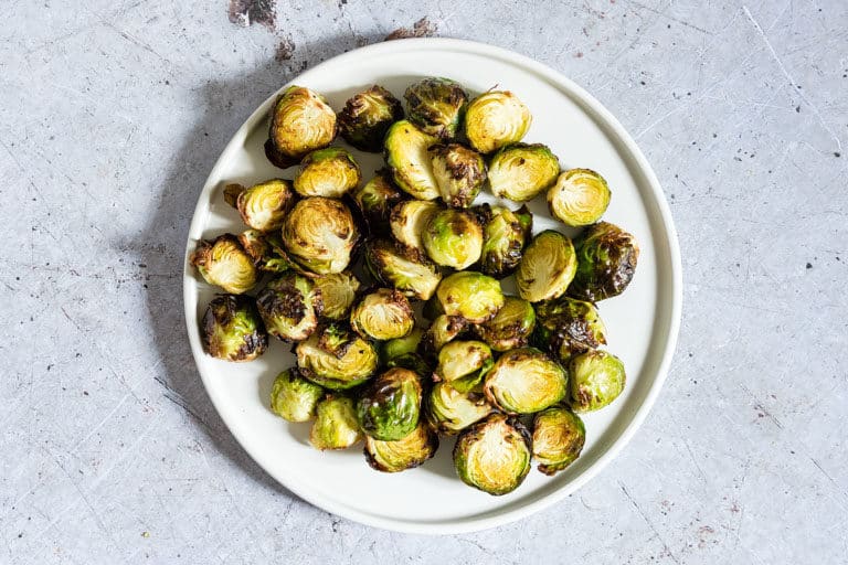 landscape image of cooked brussel sprouts on white plate