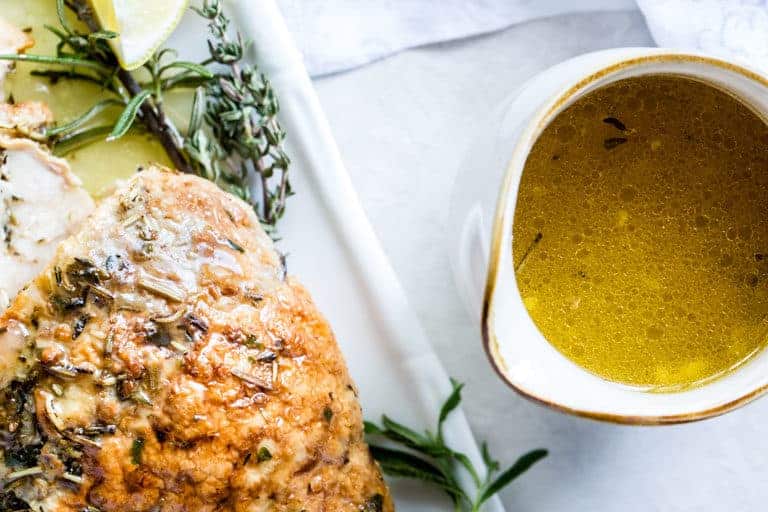 close-up of the completed Instant Pot Turkey Breast next to a white pitcher filled with the garlic butter gravy