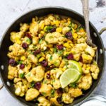 a bowl of air fryer cauliflower curry with a spoon and lime