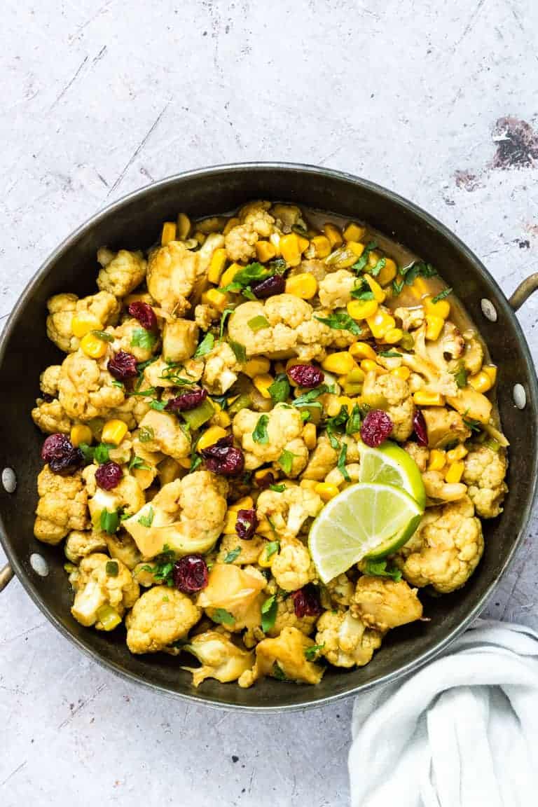 Homemade Cauliflower curry in a bowl garnished with limes