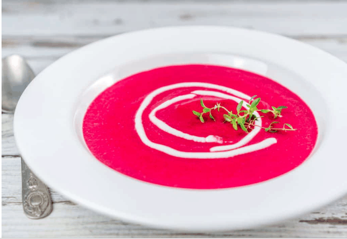 beet and butternut squash soup served in a white bowl