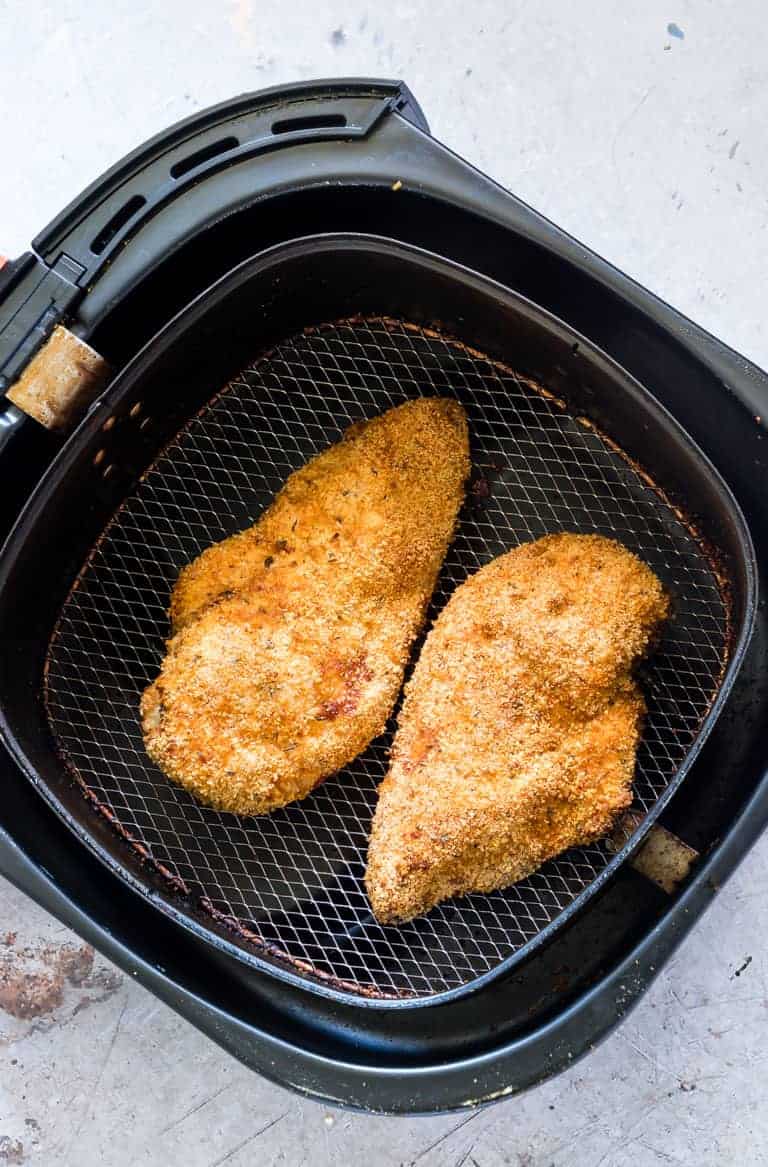 two whole pieces of air fryer chicken breast inside the air fryer basket