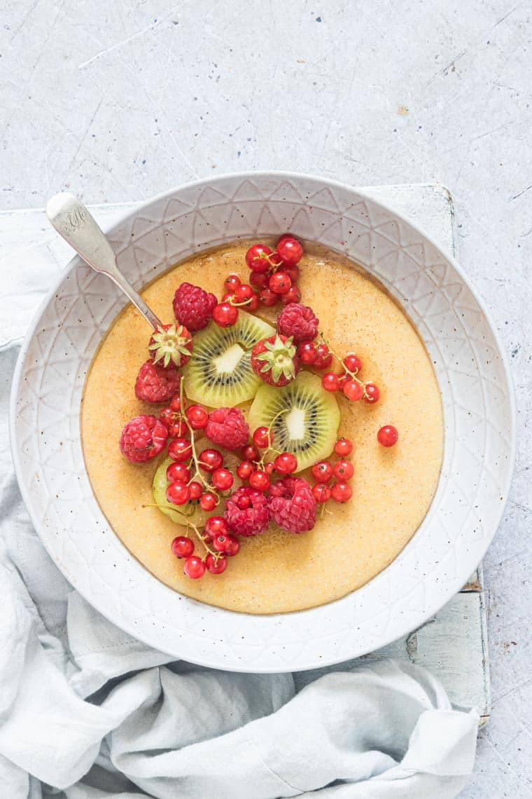 sweet cornmeal porridge in a bowl with berries and kiwi 