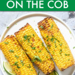 CORN ON THE COB TOPPED WITH CILANTRO ON A PLATE