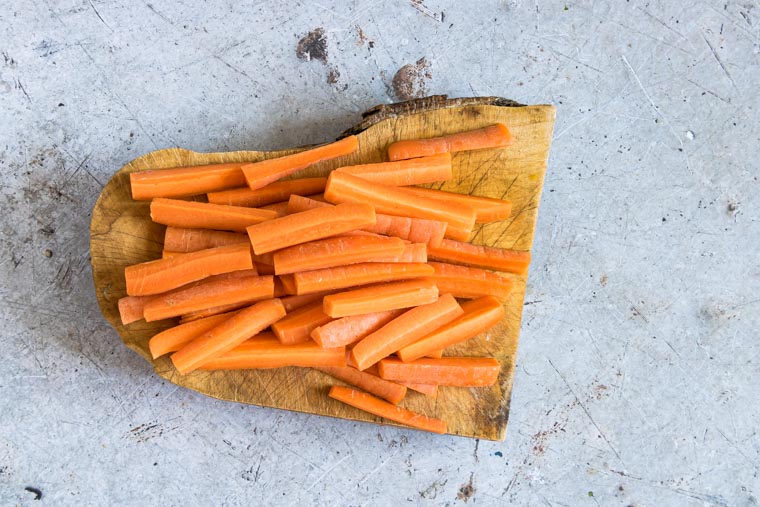 carrots cut into sticks on a live edge wooden cutting board