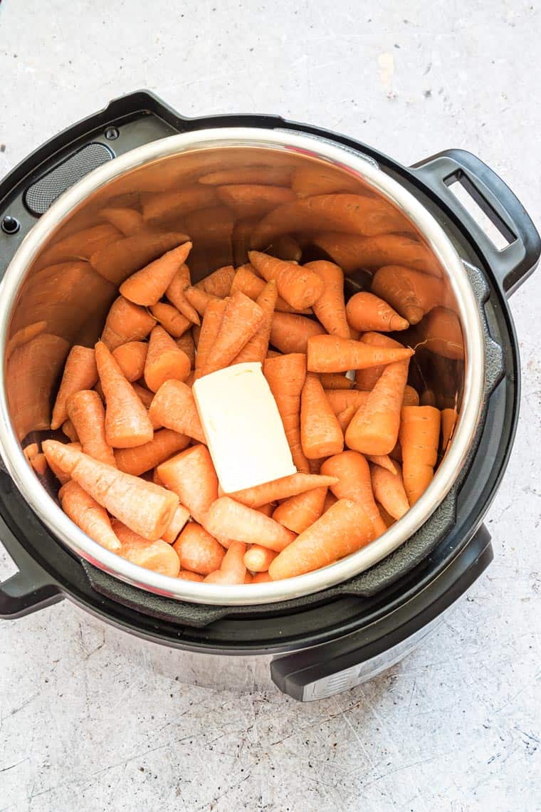 carrots on butter added to the Instant Pot insert and ready to be cooked.