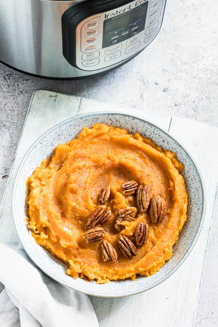 mashed sweet potatoes in a serving dish next to the Instant Pot