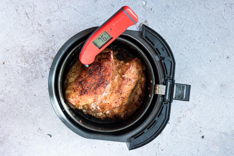 top down view of turkey breast inside the air fryer basket with a digital meat thermometer inserted