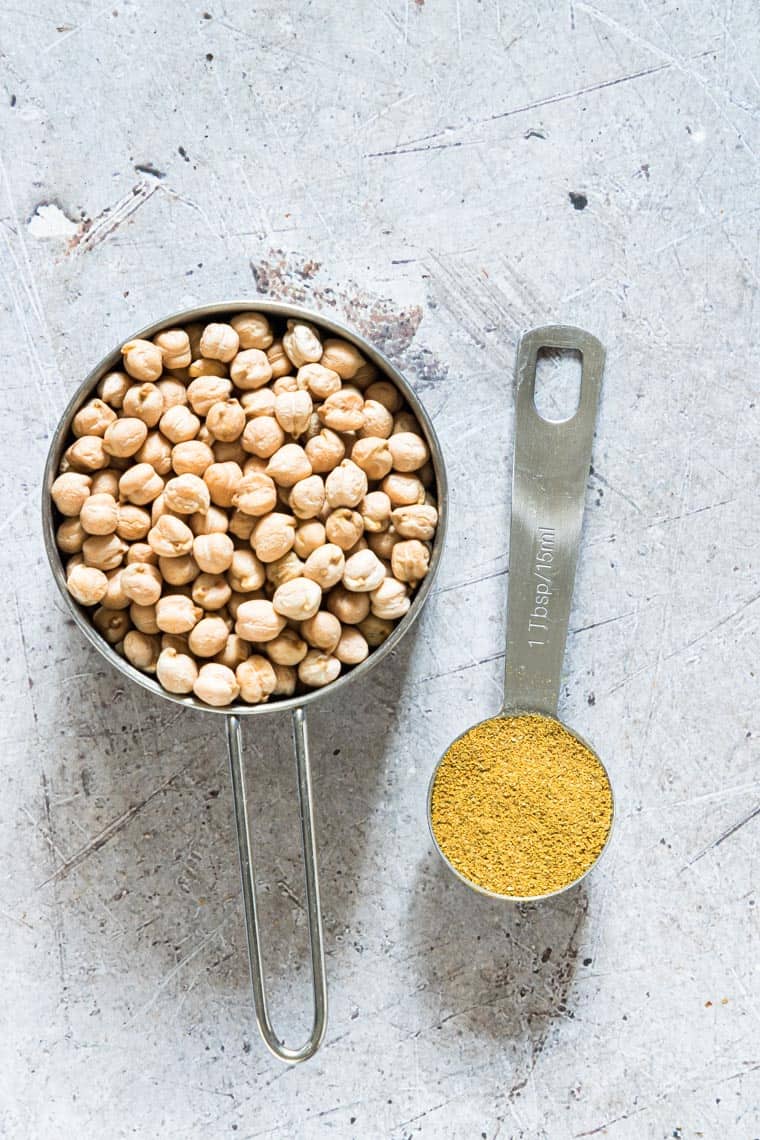 one measure cup filled with chickpeas and a tablespoons filled with curry powder