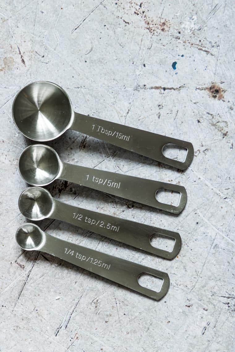 silver teaspoon and tablespoon measuring spoons lined up on a counter top