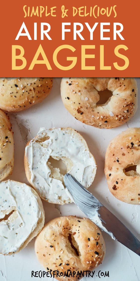 top down view of several bagels with one cut in half and spread with cream cheese