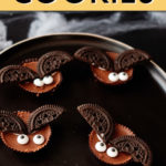 four bat cookies sitting on a black plate