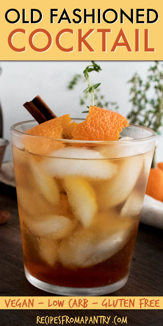 a glass of iced old fashioned cocktail garnished with orange peel