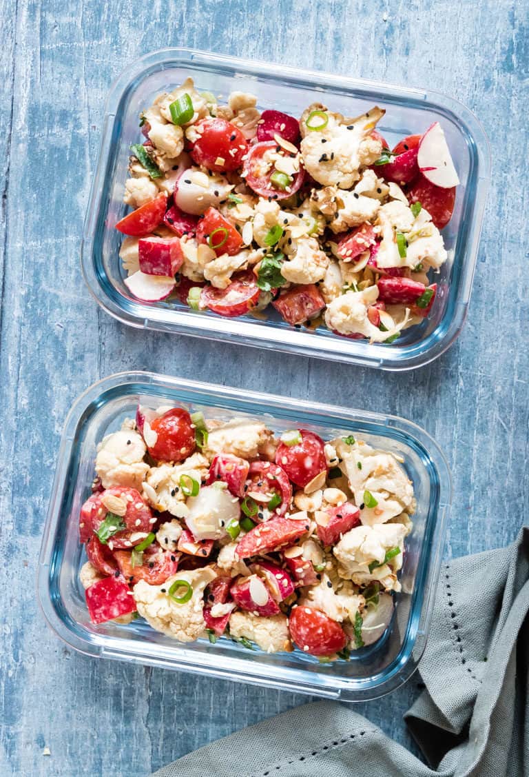 two glass meal prep storage containers filled with roasted cauliflower salad