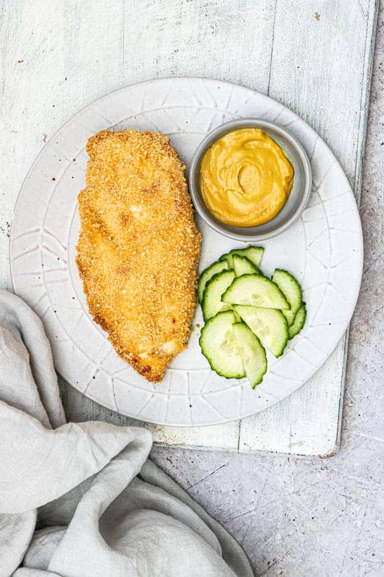 one finished piece of bread chicken served with cucumbers and dipping sauce