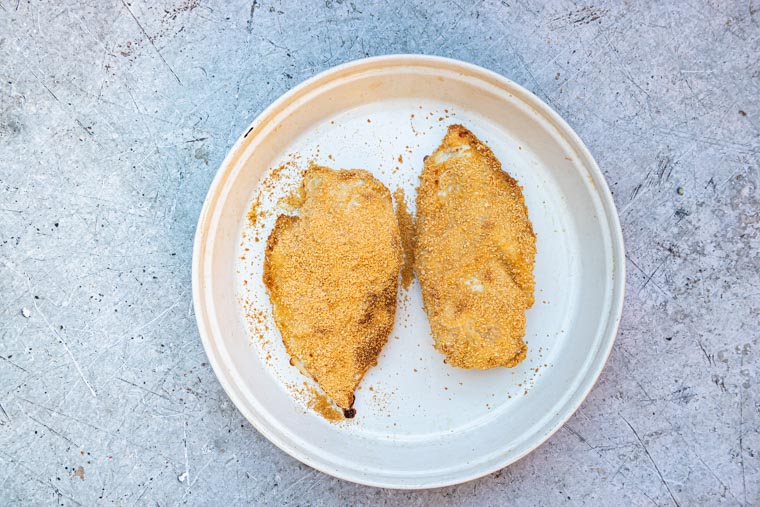 two pieces of breaded chicken on a white plate