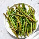 Cooked Air Fryer Green Beans served on a white dinner plate with a cloth white napkin