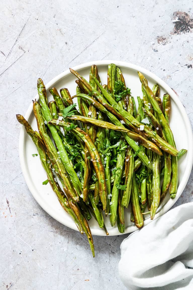 Cooked Air Fryer Green Beans served on a white dinner plate with a cloth white napkin