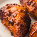 Smoked chicken breasts with a glossy barbecue glaze on a white plate.